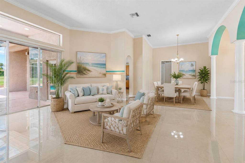 A bright, open-concept living and dining area with tile floors, neutral walls, and coastal decor — 18107 EMERALD BAY STREET, TAMPA, FL