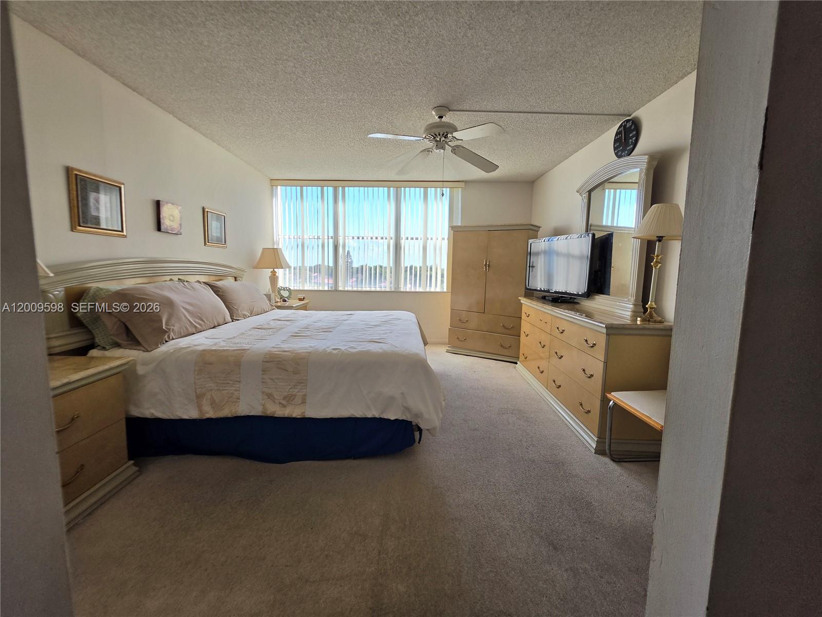 A bedroom features a bed, dresser, armoire, ceiling fan, and large windows with vertical blinds — 3771 Environ Blvd # 649, Lauderhill FL 33319, LAUDERHILL, FL