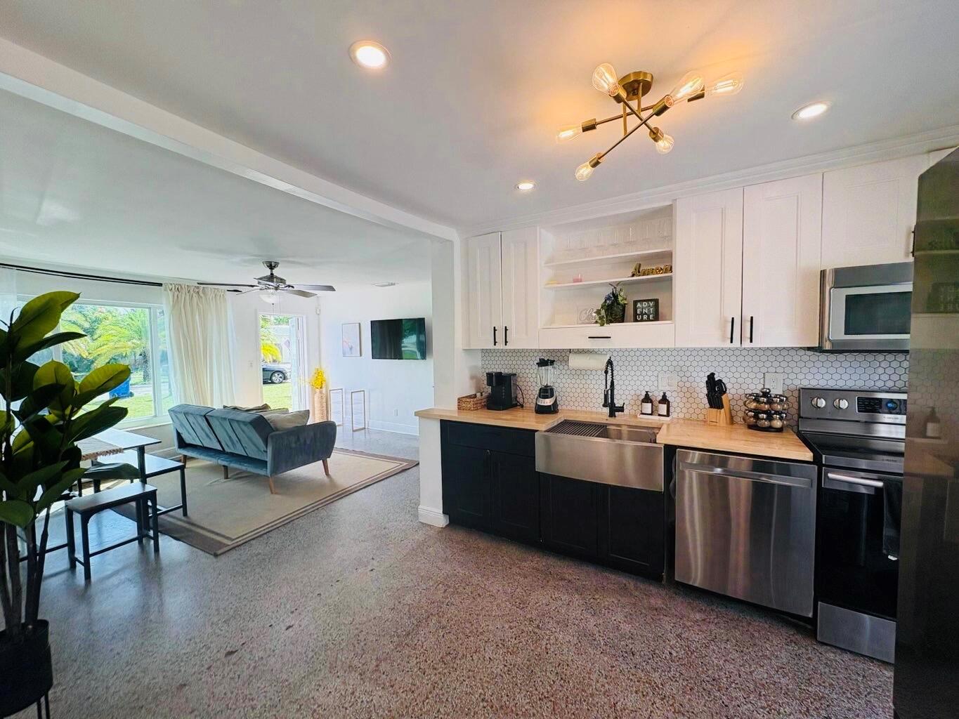 A kitchen with dark lower cabinets and white upper cabinets opens into a living area — 2711 NE 11th Terrace, Pompano Beach FL 33064, POMPANO BEACH, FL