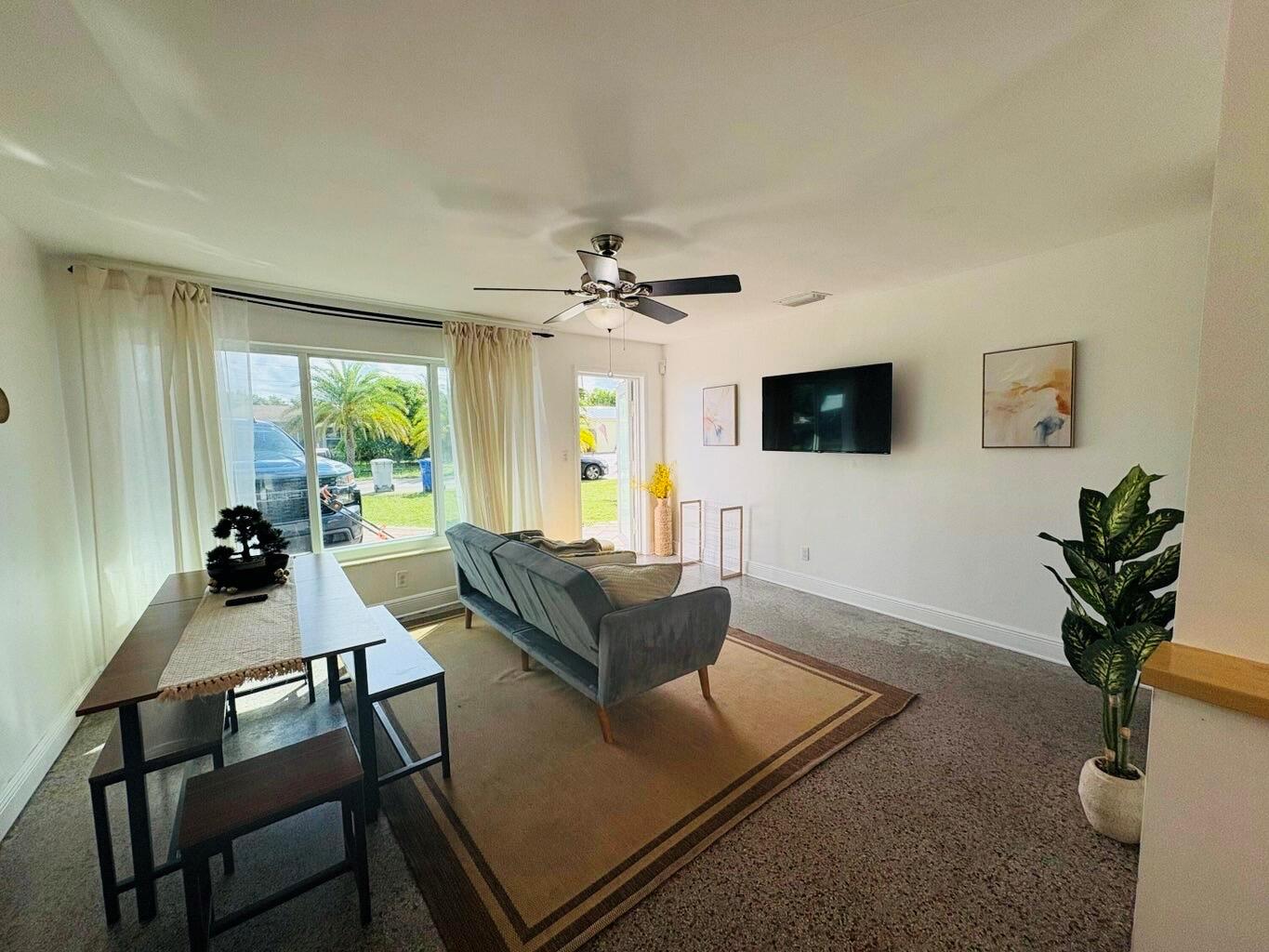 A living and dining area features a grey sofa, a dining table, and a wall-mounted television — 2711 NE 11th Terrace, Pompano Beach FL 33064, POMPANO BEACH, FL