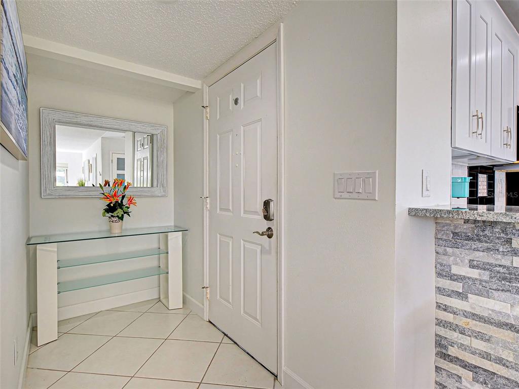 An entryway features a glass console table, a mirror, and a white door — 262 CERROMAR WAY S UNIT 53, VENICE, FL