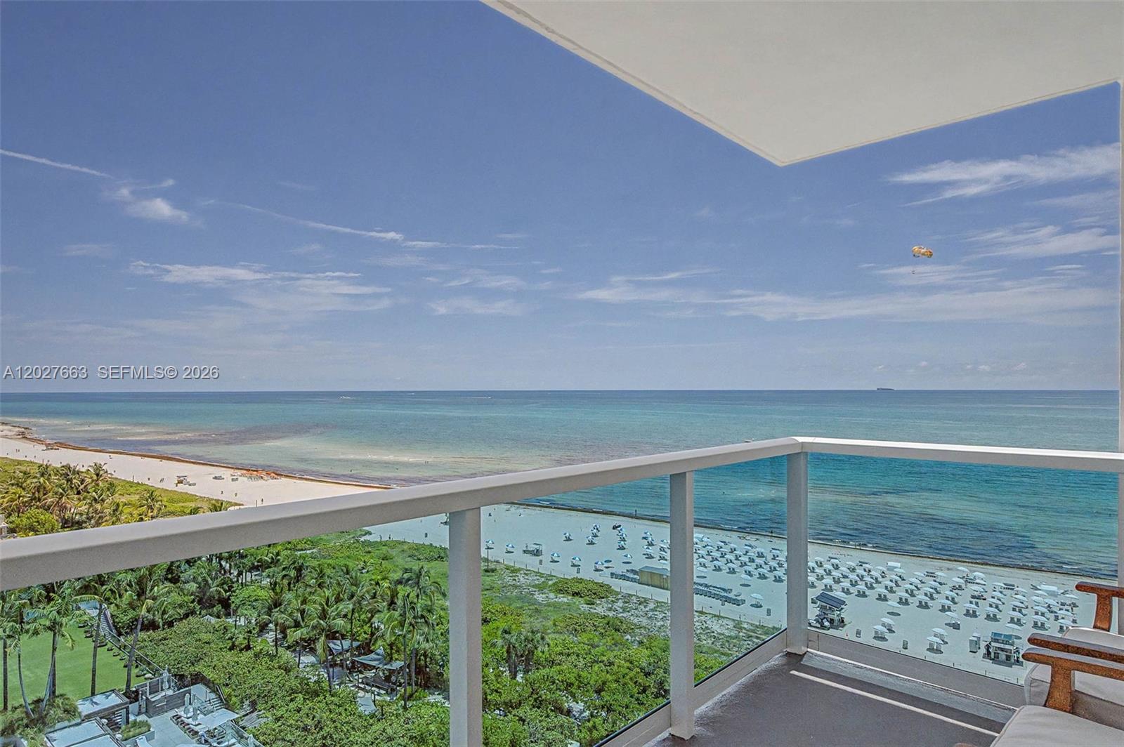 A high-angle view from a balcony overlooking a beach with umbrellas and the ocean — 2301 Collins Ave # 1210, Miami Beach FL 33139, MIAMI BEACH, FL