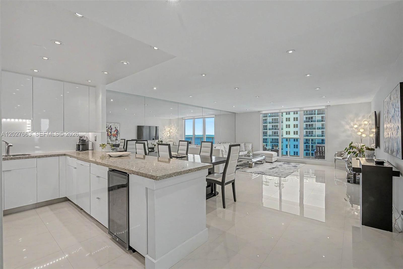 A modern open-concept kitchen and living area with white cabinetry, granite countertops, and ocean views — 2301 Collins Ave # 1210, Miami Beach FL 33139, MIAMI BEACH, FL