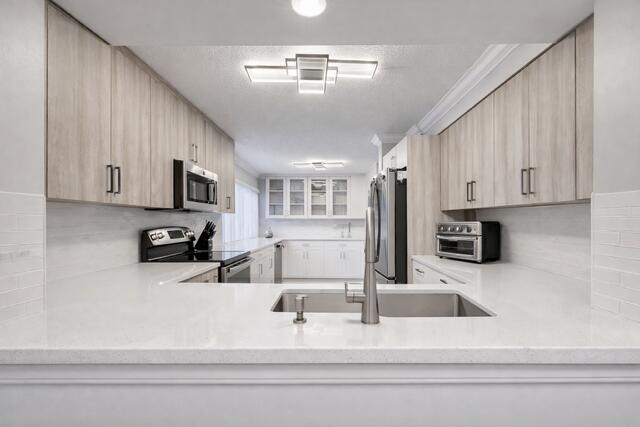A modern kitchen features light wood cabinets, white quartz countertops, and stainless steel appliances — 11262 Green Lake Drive # 204, Boynton Beach FL 33437, BOYNTON BEACH, FL