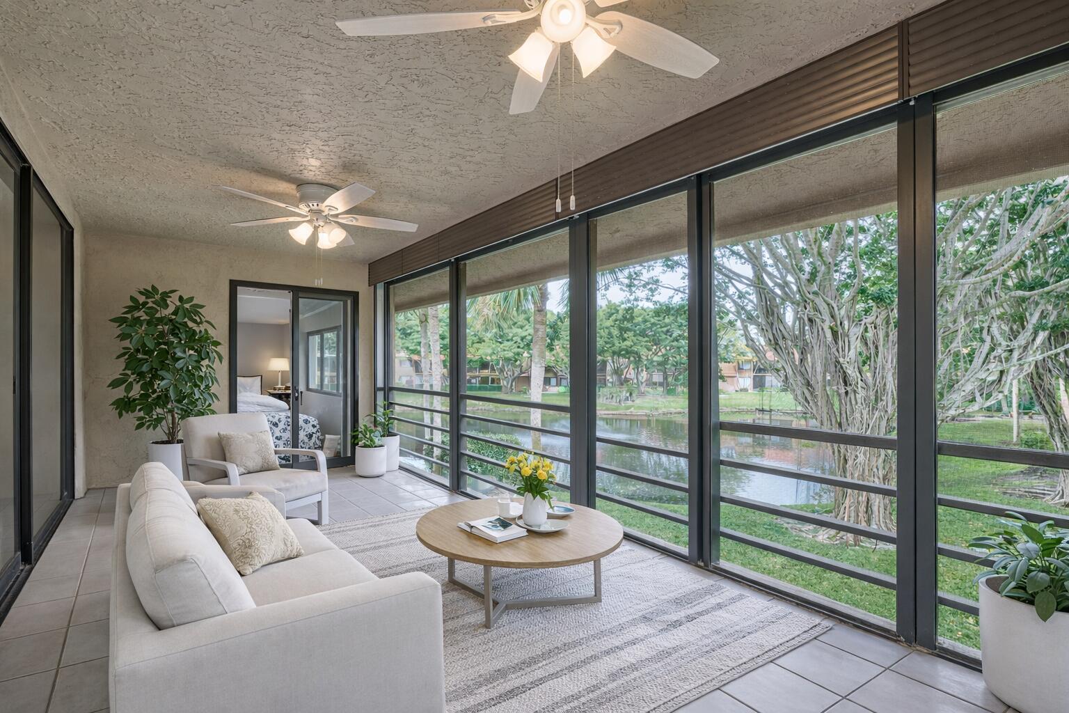 A screened-in patio features a sofa, coffee table, ceiling fans, and a view of water — 11262 Green Lake Drive # 204, Boynton Beach FL 33437, BOYNTON BEACH, FL