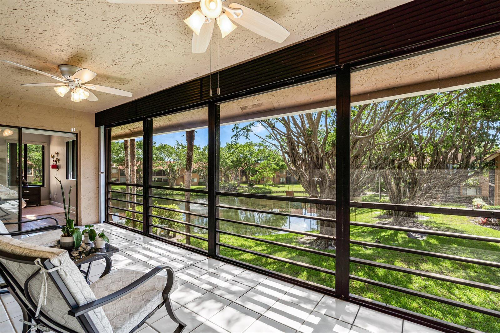 A screened-in patio with tile flooring overlooks a pond and trees — 11262 Green Lake Drive # 204, Boynton Beach FL 33437, BOYNTON BEACH, FL