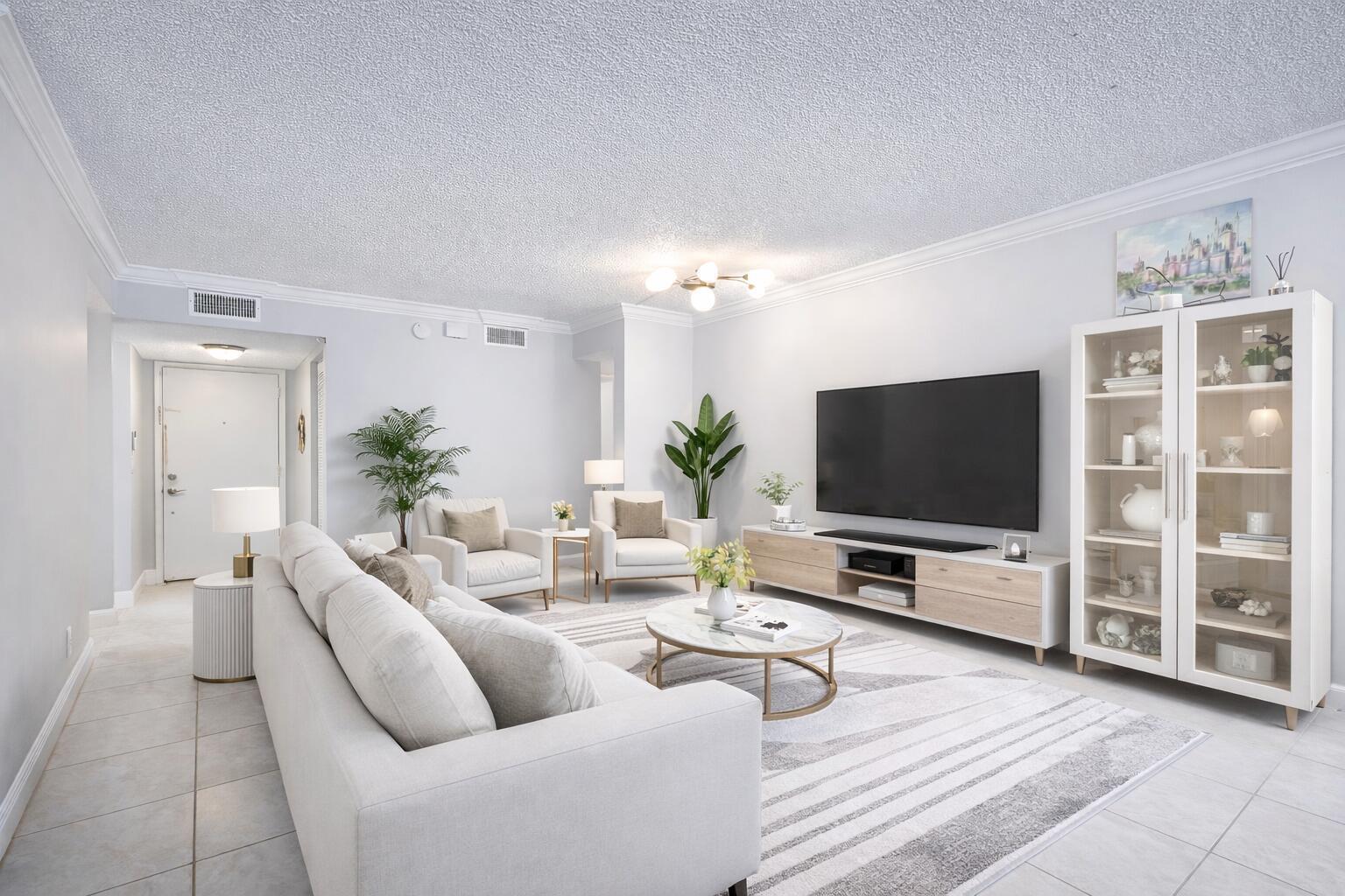 A bright living room features a white sofa, two armchairs, a television, and a display cabinet — 11262 Green Lake Drive # 204, Boynton Beach FL 33437, BOYNTON BEACH, FL