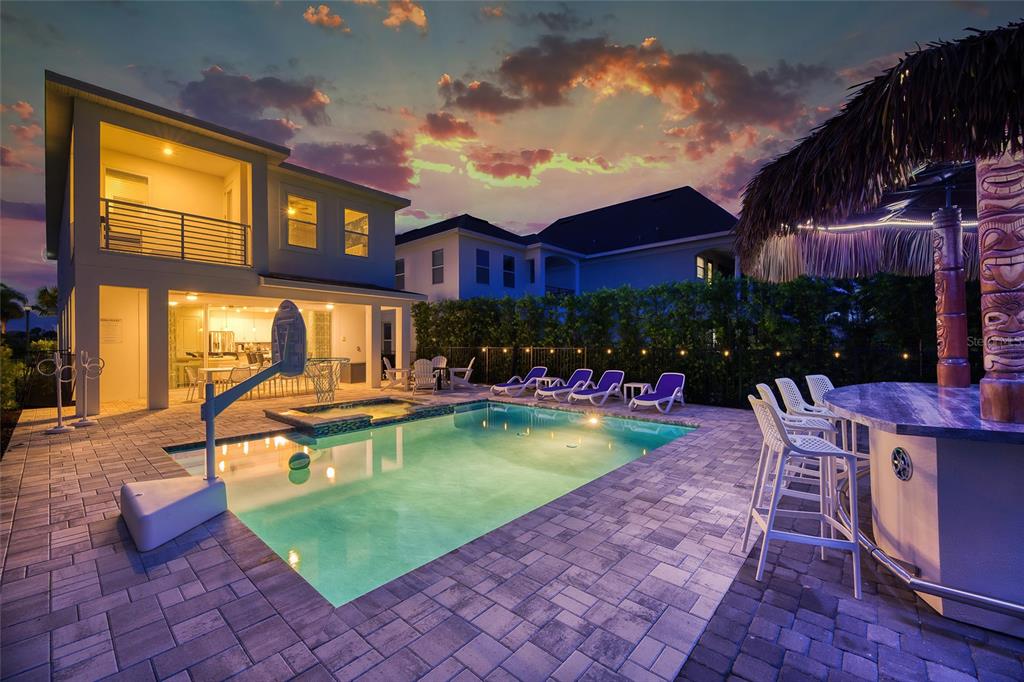 A backyard pool area features a tiki bar, lounge chairs, and a two-story house exterior — 801 GOLDEN BEAR DRIVE, KISSIMMEE, FL