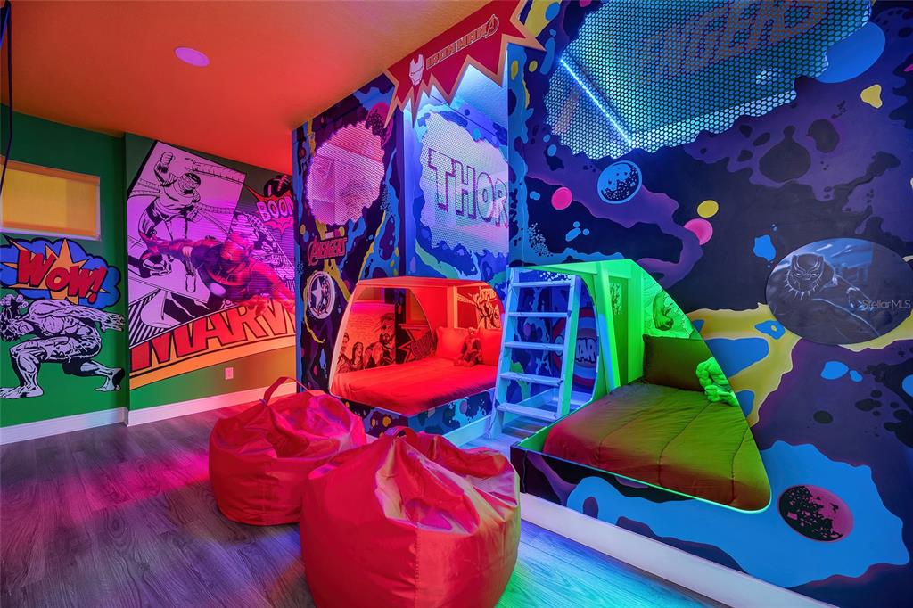 A themed bedroom features two beds, beanbag chairs, and vibrant Marvel comic book wall murals — 801 GOLDEN BEAR DRIVE, KISSIMMEE, FL