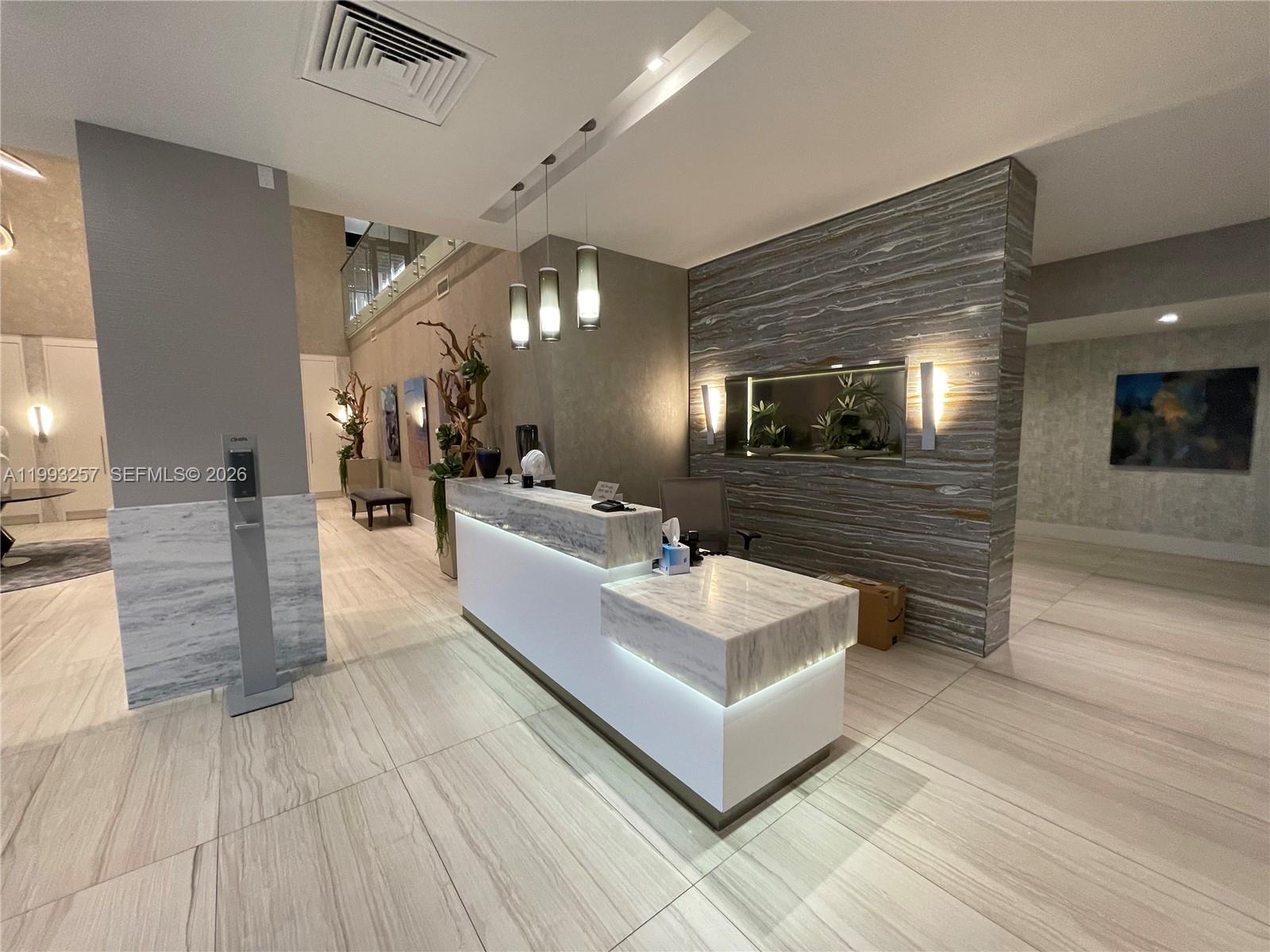 A modern reception area features a marble-topped desk, stone accent wall, and recessed lighting — 2301 S Ocean Dr # 607, Hollywood FL 33019, HOLLYWOOD, FL