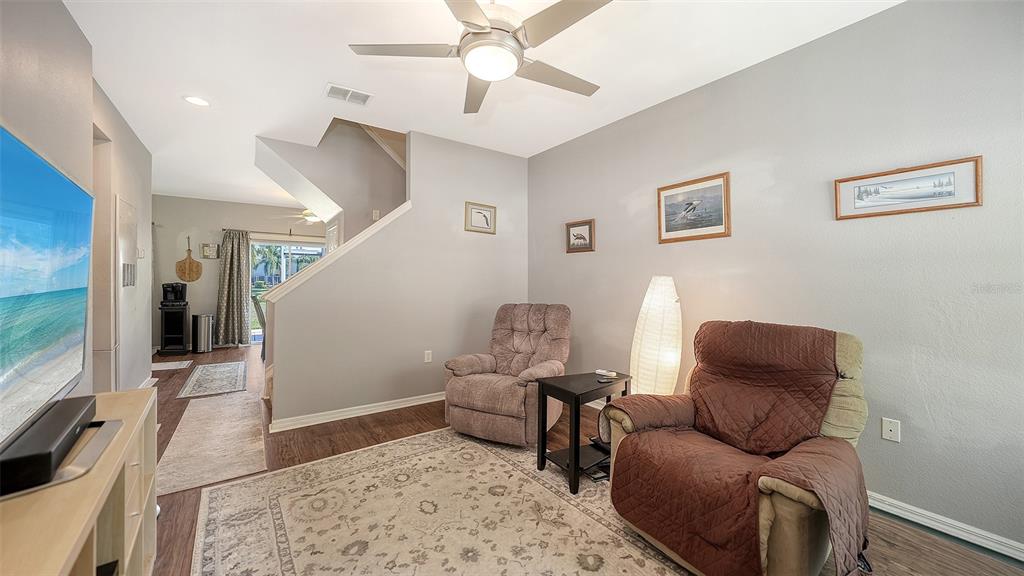 A living room features two recliners, a ceiling fan, and stairs leading to an upper level — 7721 PLANTATION CIRCLE, BRADENTON, FL