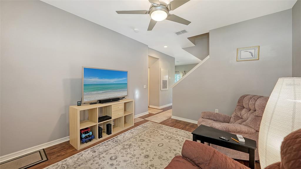 A living room features a television on a storage unit, a recliner, and a ceiling fan — 7721 PLANTATION CIRCLE, BRADENTON, FL