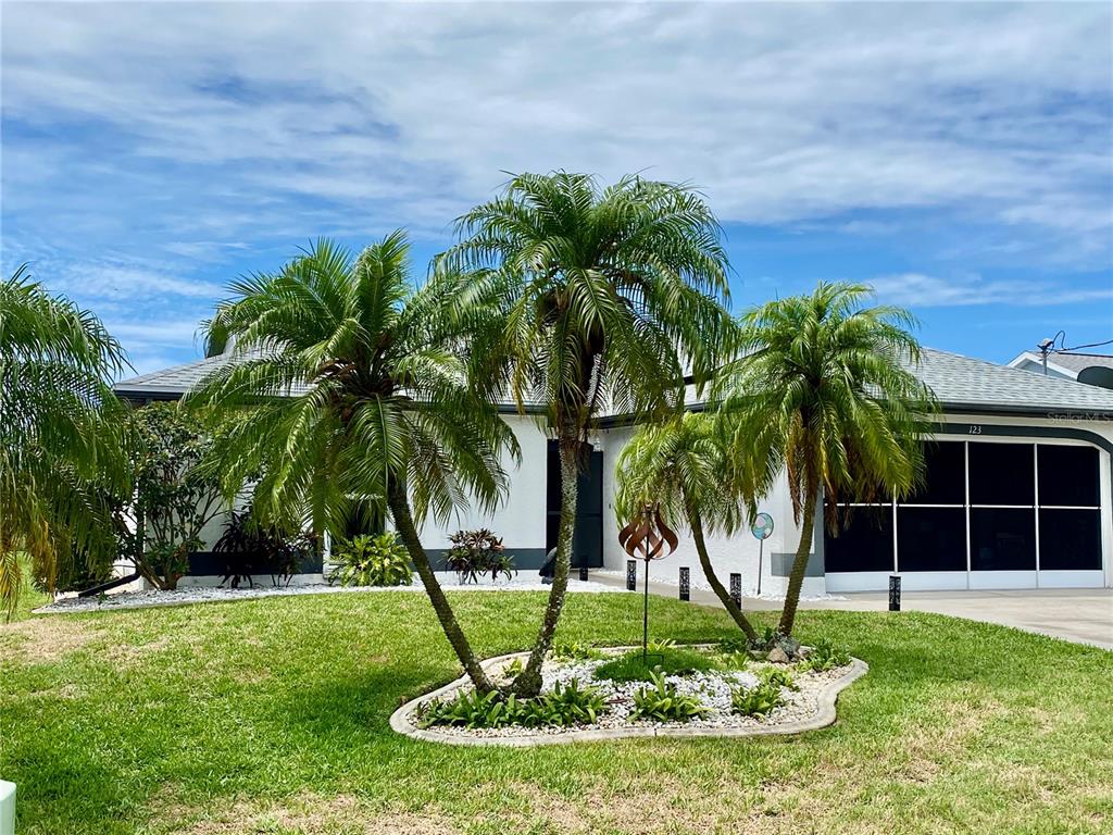 A single-story house with a white exterior, palm trees, and a screened-in garage — 123 KINGS DRIVE, ROTONDA WEST, FL