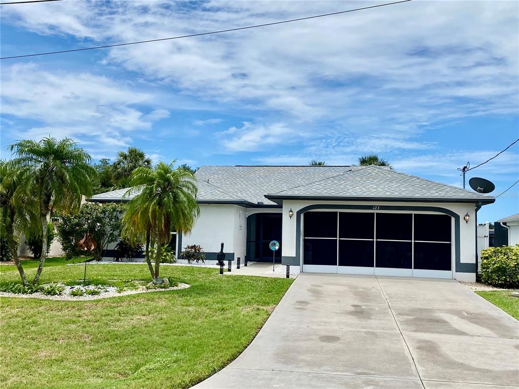 A single-story house with a screened garage, white stucco walls, and palm trees in the yard — 123 KINGS DRIVE, ROTONDA WEST, FL