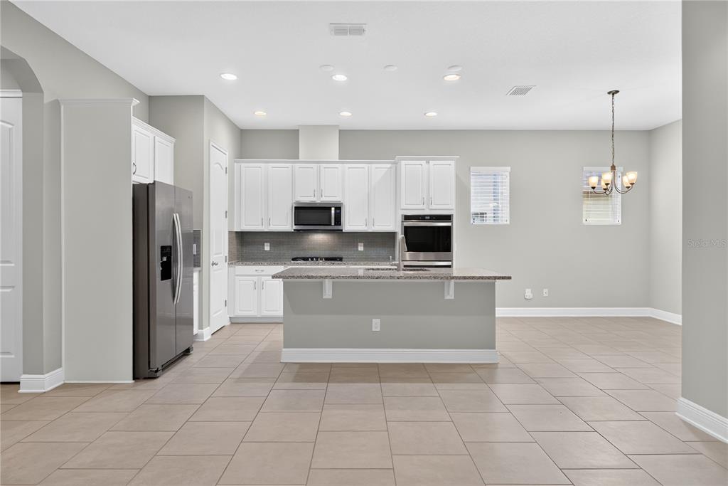 A kitchen with white cabinets, stainless steel appliances, a center island, and light tile flooring — 16954 TRADEWIND POINT, WINTER GARDEN, FL