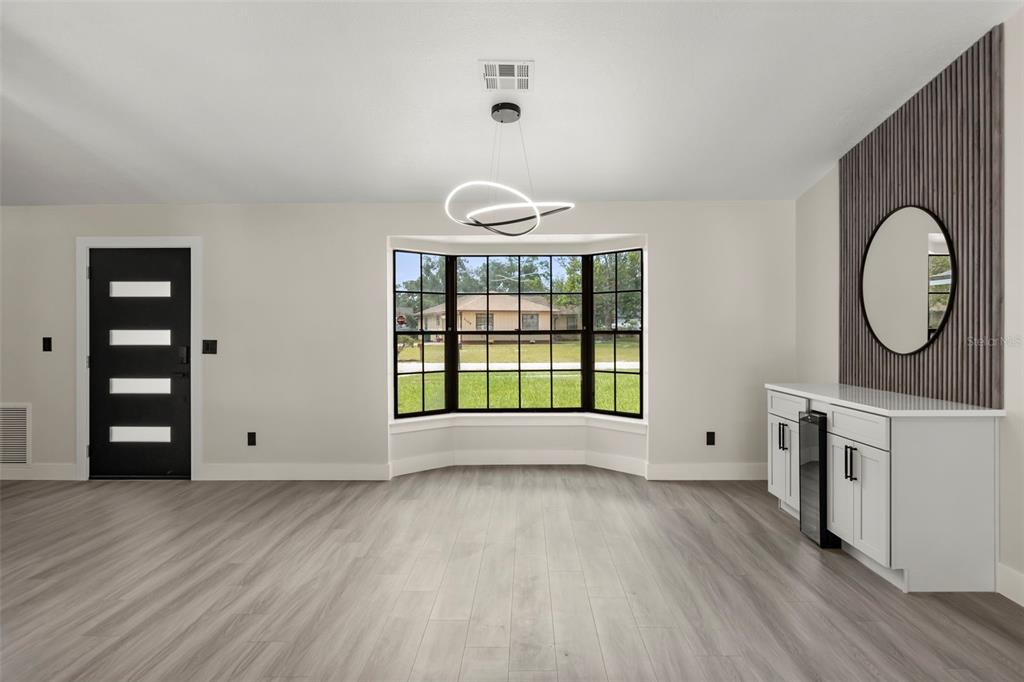 A dining area features light wood flooring, a bay window, a modern chandelier, and cabinetry — 3007 FAYSON CIRCLE, DELTONA, FL