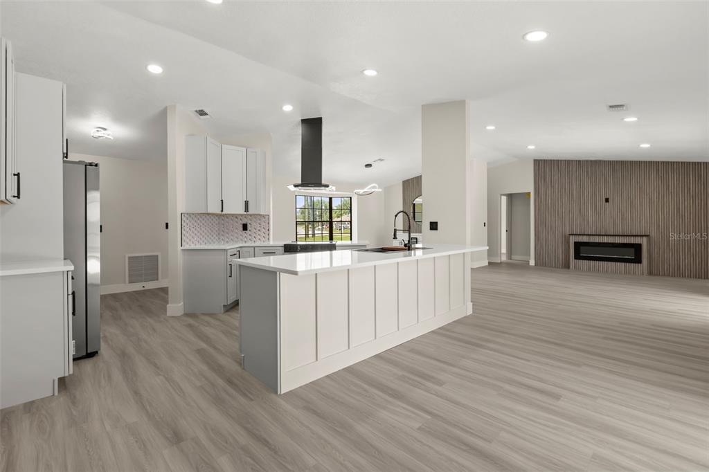 A modern kitchen features a white island, light gray cabinetry, and wood-look flooring — 3007 FAYSON CIRCLE, DELTONA, FL