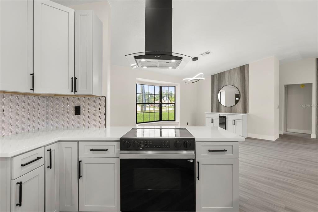 A modern kitchen features white cabinetry, a black range hood, and a tiled backsplash — 3007 FAYSON CIRCLE, DELTONA, FL