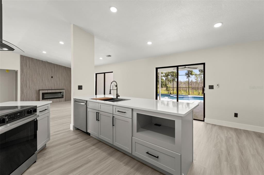 A modern kitchen features light gray cabinets, white countertops, and a view of a pool — 3007 FAYSON CIRCLE, DELTONA, FL