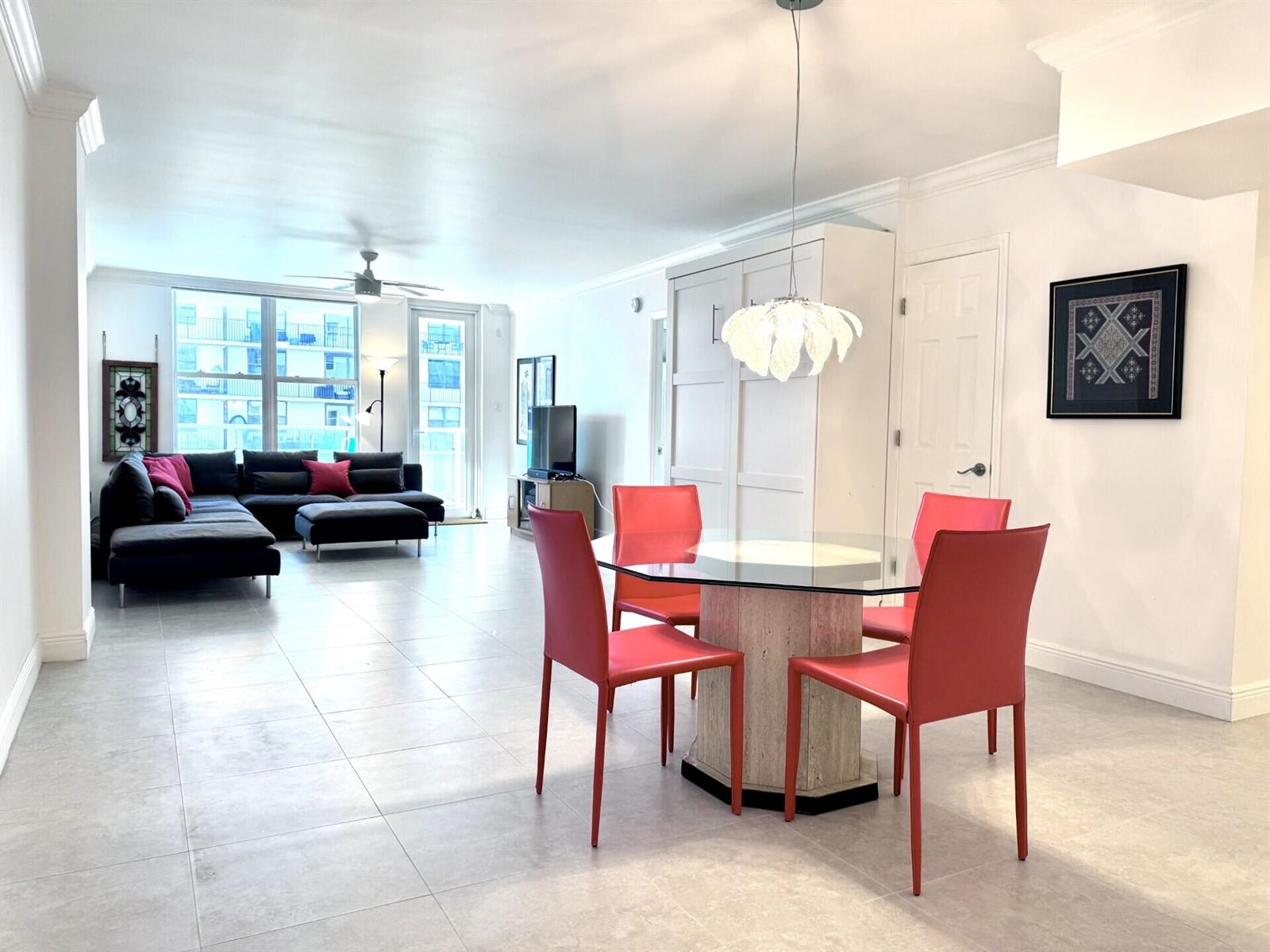 A bright living and dining area features white tile floors, red chairs, and a sectional — 3450 S Ocean Boulevard # 121, Palm Beach FL 33480, PALM BEACH, FL