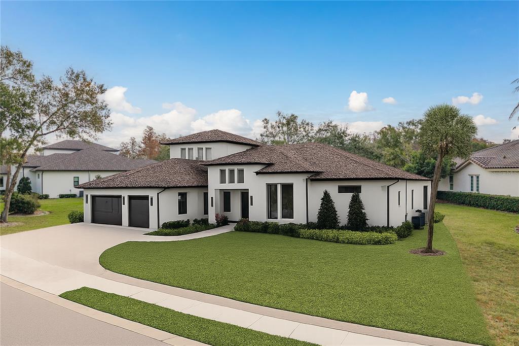 A modern single-story house with a white exterior, dark roof, and a two-car garage — 3926 COVE LAKE PLACE, LAND O LAKES, FL