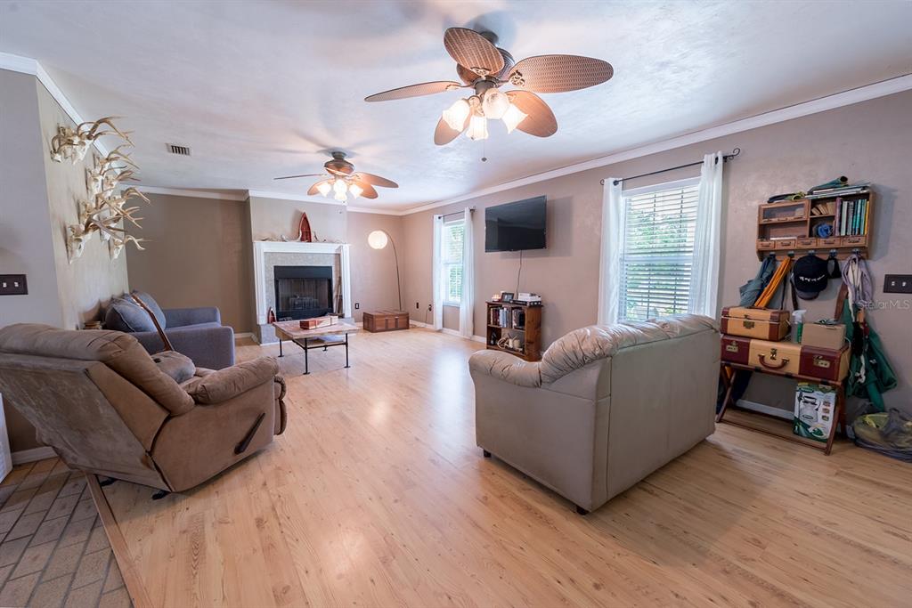 A living room features light wood flooring, two ceiling fans, a fireplace, and two sofas — 5876 SW 52ND TERRACE, LAKE BUTLER, FL