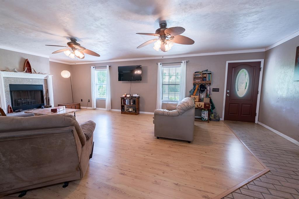 A living room features light wood flooring, a fireplace, two ceiling fans, and a front door — 5876 SW 52ND TERRACE, LAKE BUTLER, FL