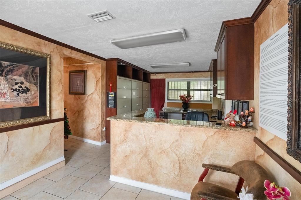 A reception area features a granite-topped desk, faux-finish walls, tile flooring, and built-in cabinetry — 4900 33RD AVENUE N, ST PETERSBURG, FL