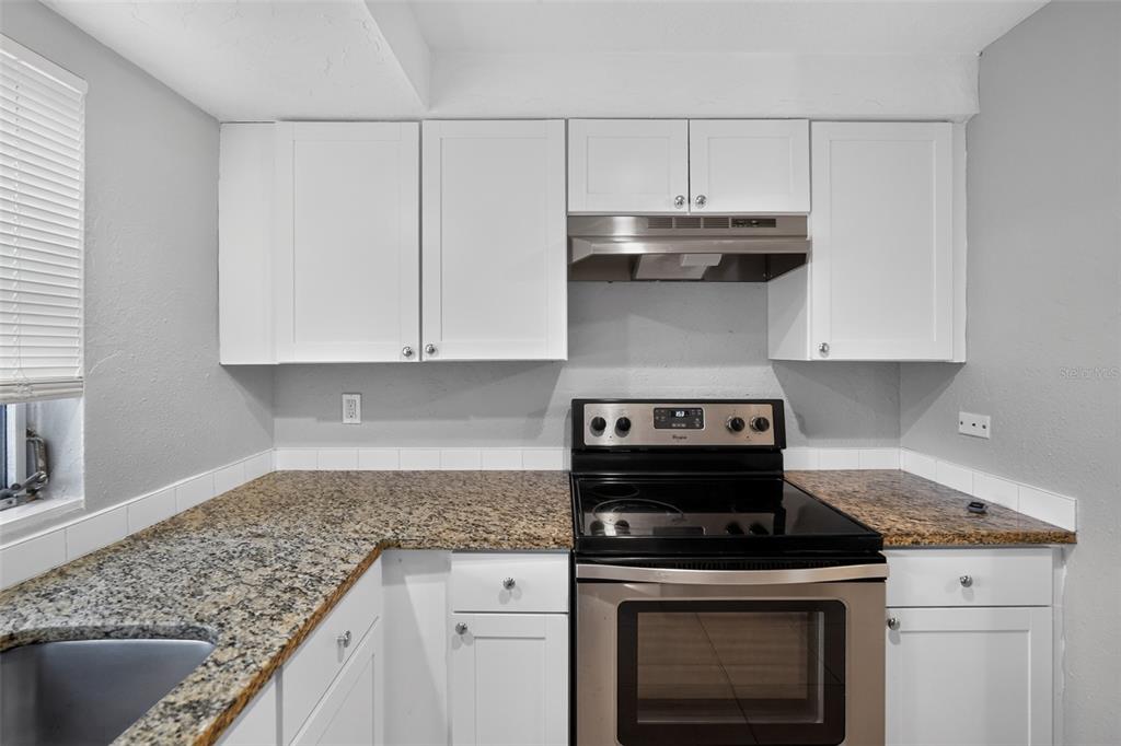 A kitchen features white cabinets, granite countertops, and a stainless steel range with a hood — 3834 WARREN RIDGE STREET, SARASOTA, FL