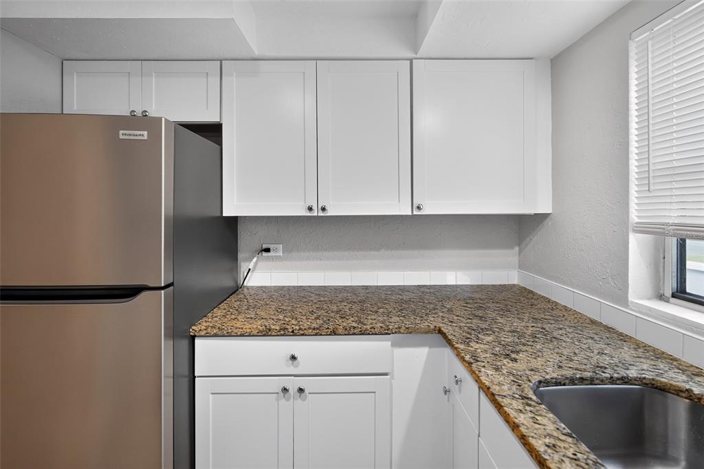 A kitchen features white cabinets, granite countertops, a stainless steel refrigerator, and a sink — 3834 WARREN RIDGE STREET, SARASOTA, FL