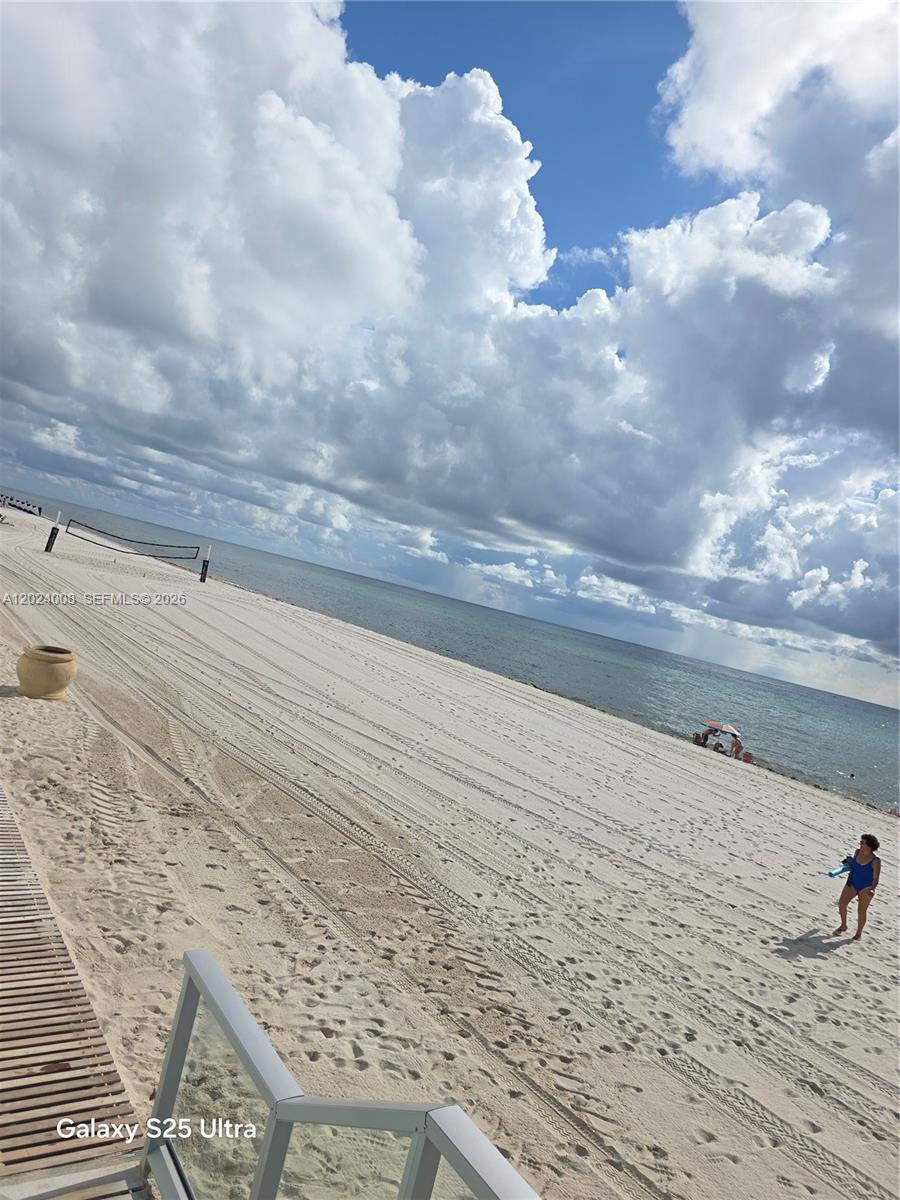 A view of a sandy beach with a volleyball net and the ocean under cloudy skies — 3725 S Ocean Dr # 617, Hollywood FL 33019, HOLLYWOOD, FL