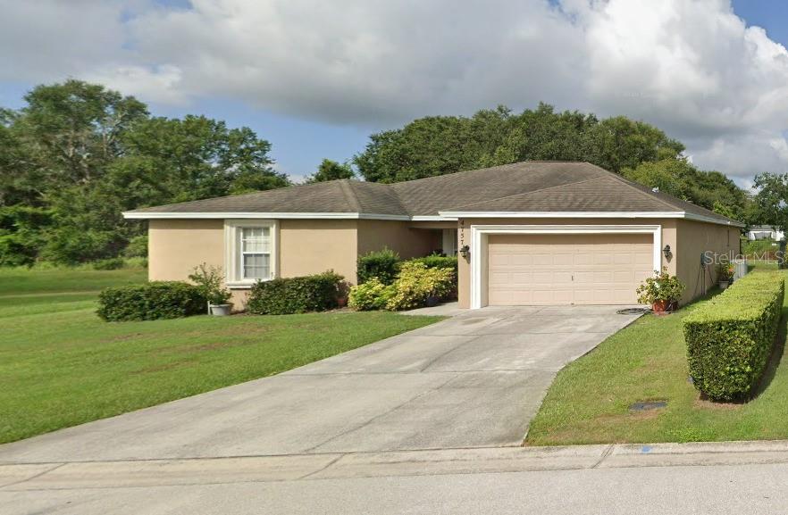 A single-story house with a beige stucco exterior, a two-car garage, and a concrete driveway — 4757 ACORN DRIVE, MULBERRY, FL