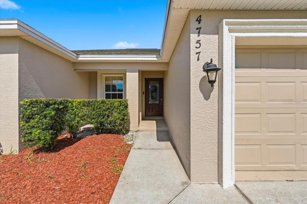A concrete walkway leads to the front entrance of a house with a garage — 4757 ACORN DRIVE, MULBERRY, FL