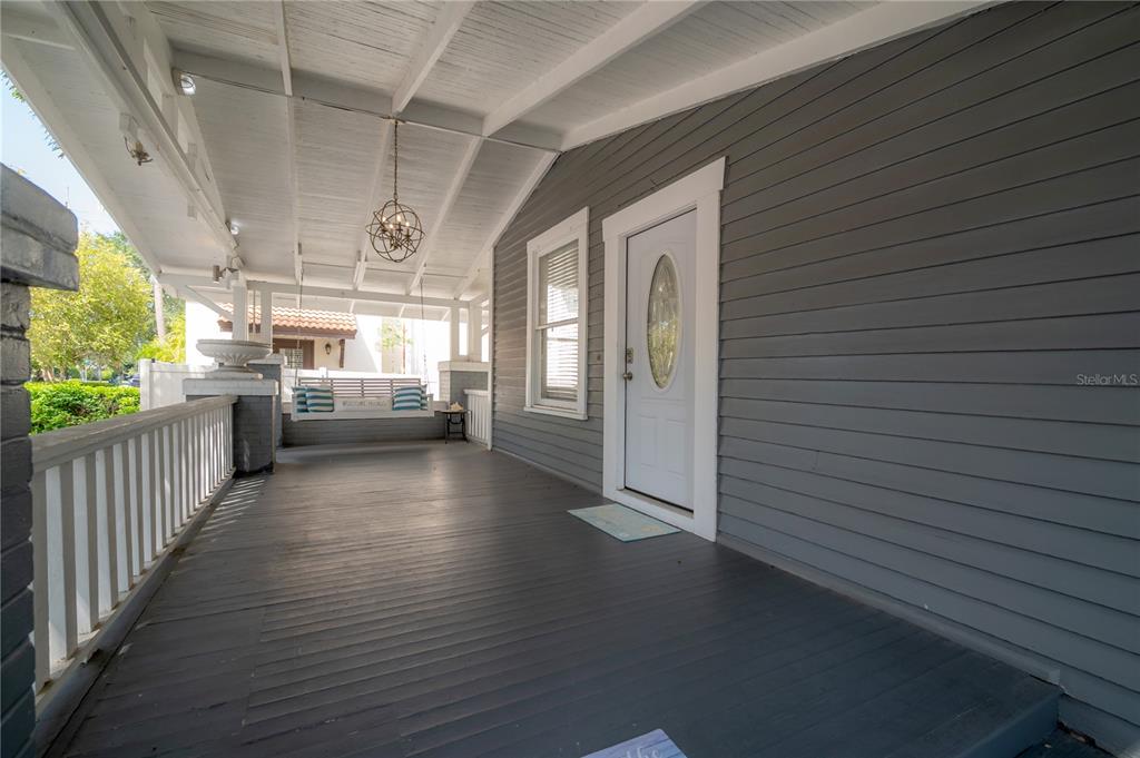 A covered front porch features gray wood siding, a white door, and a hanging swing — 2921 W EL PRADO BOULEVARD, TAMPA, FL