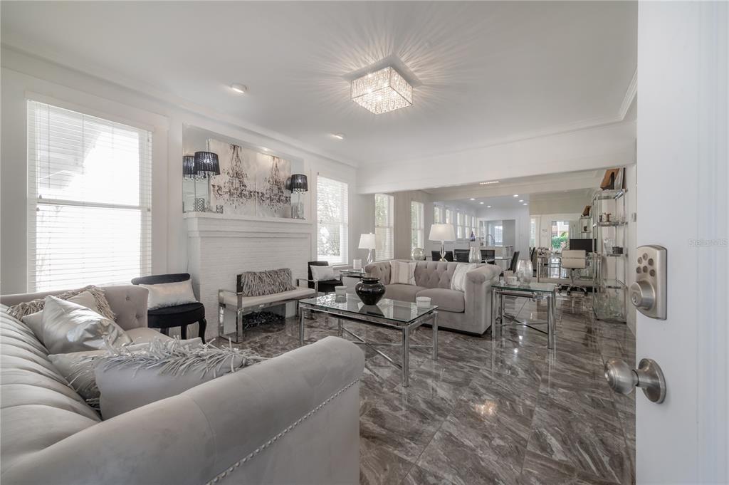 A living room features gray tufted sofas, a glass coffee table, and marble-look tile flooring — 2921 W EL PRADO BOULEVARD, TAMPA, FL