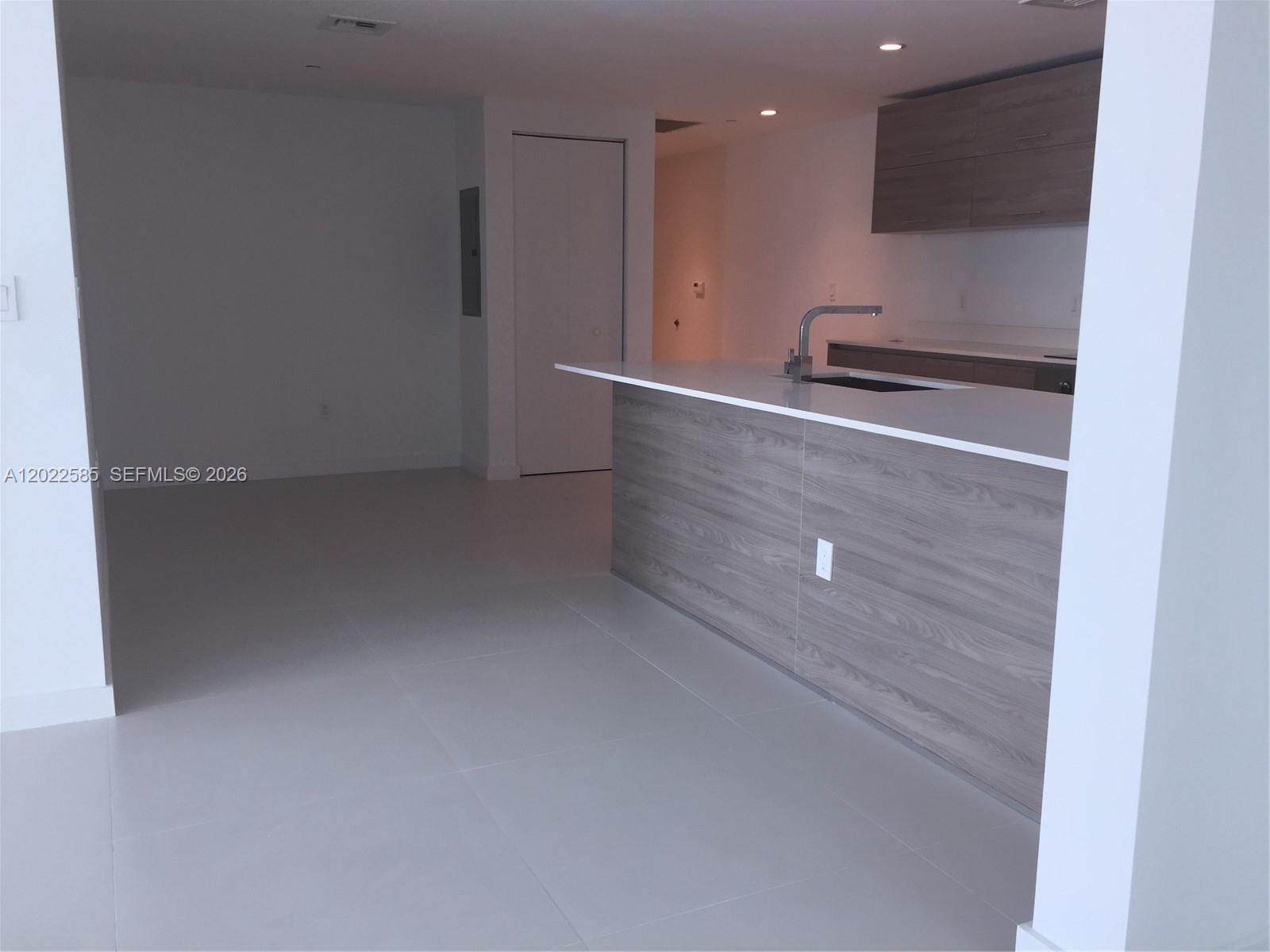 A modern kitchen features a wood-grain island with a white countertop and matching wall cabinets — 1300 S Miami # 1910, Miami FL 33130, MIAMI, FL