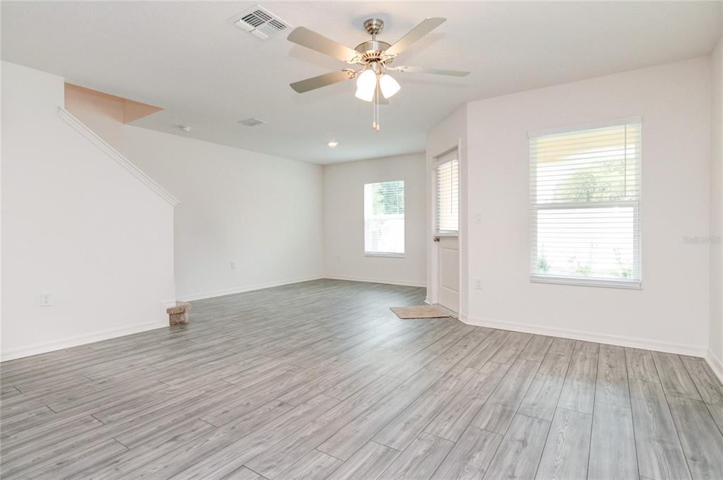 An empty room with light gray wood-look flooring, white walls, a ceiling fan, and windows — 1569 WYNFORD CIRCLE, TAVARES, FL