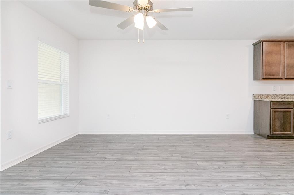An empty room with gray wood-look flooring, white walls, a ceiling fan, and kitchen cabinets — 1569 WYNFORD CIRCLE, TAVARES, FL