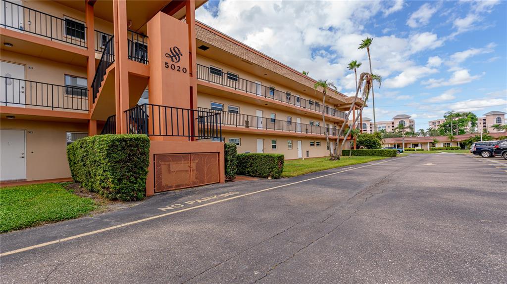 A three-story apartment building with exterior walkways and a parking lot in the foreground — 5020 BRITTANY DRIVE S UNIT 125, ST PETERSBURG, FL