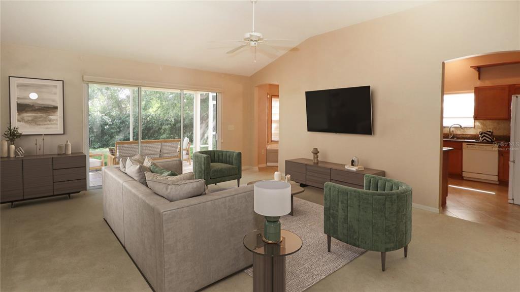 A living room with a gray sofa, two green armchairs, and a wall-mounted television — 17700 SE 92ND GRANTHAM TERRACE, THE VILLAGES, FL