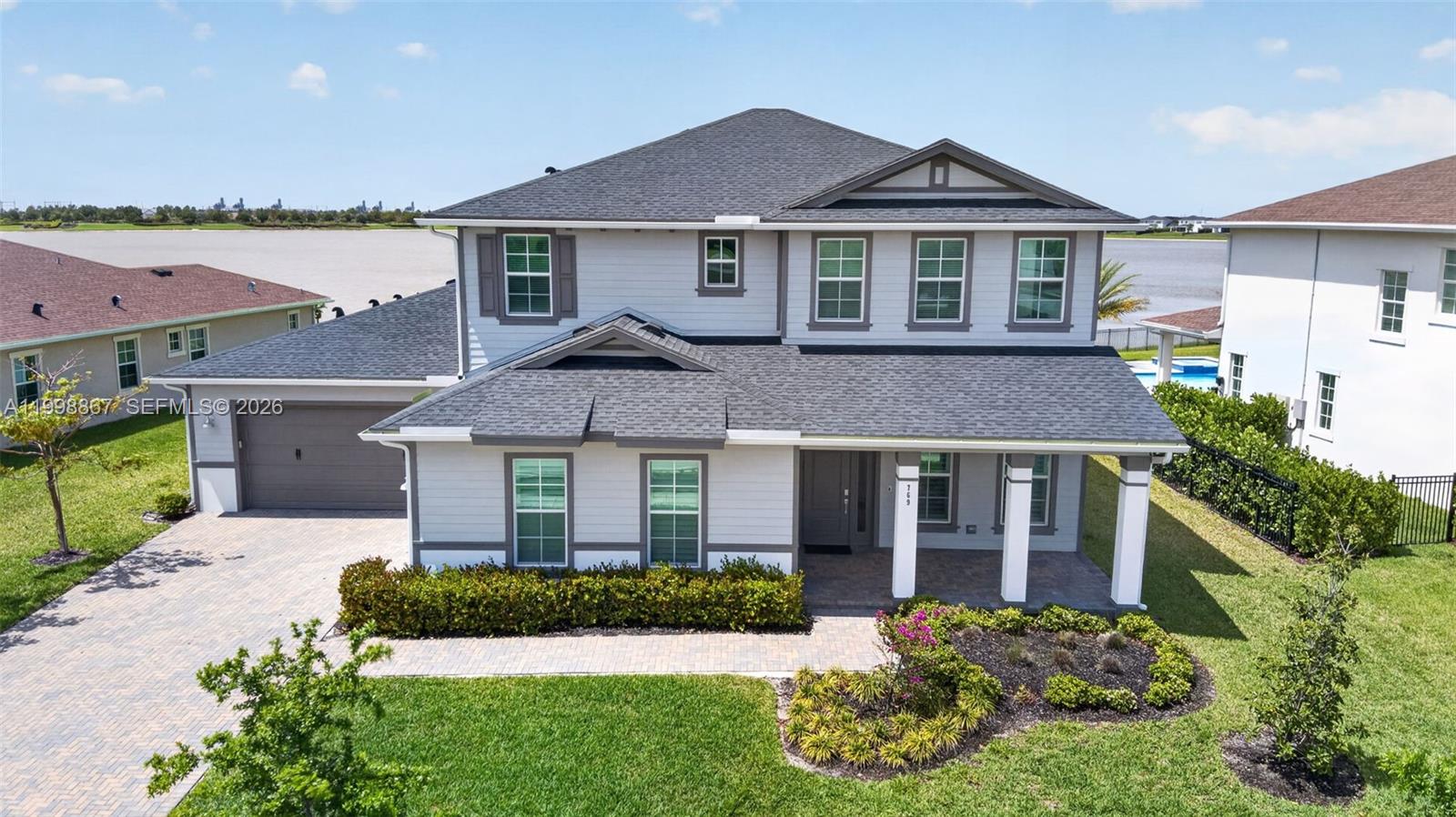 A two-story suburban house with gray siding, a dark shingled roof, and a paved driveway — 769 Hookline Cir, Loxahatchee FL 33470, LOXAHATCHEE, FL