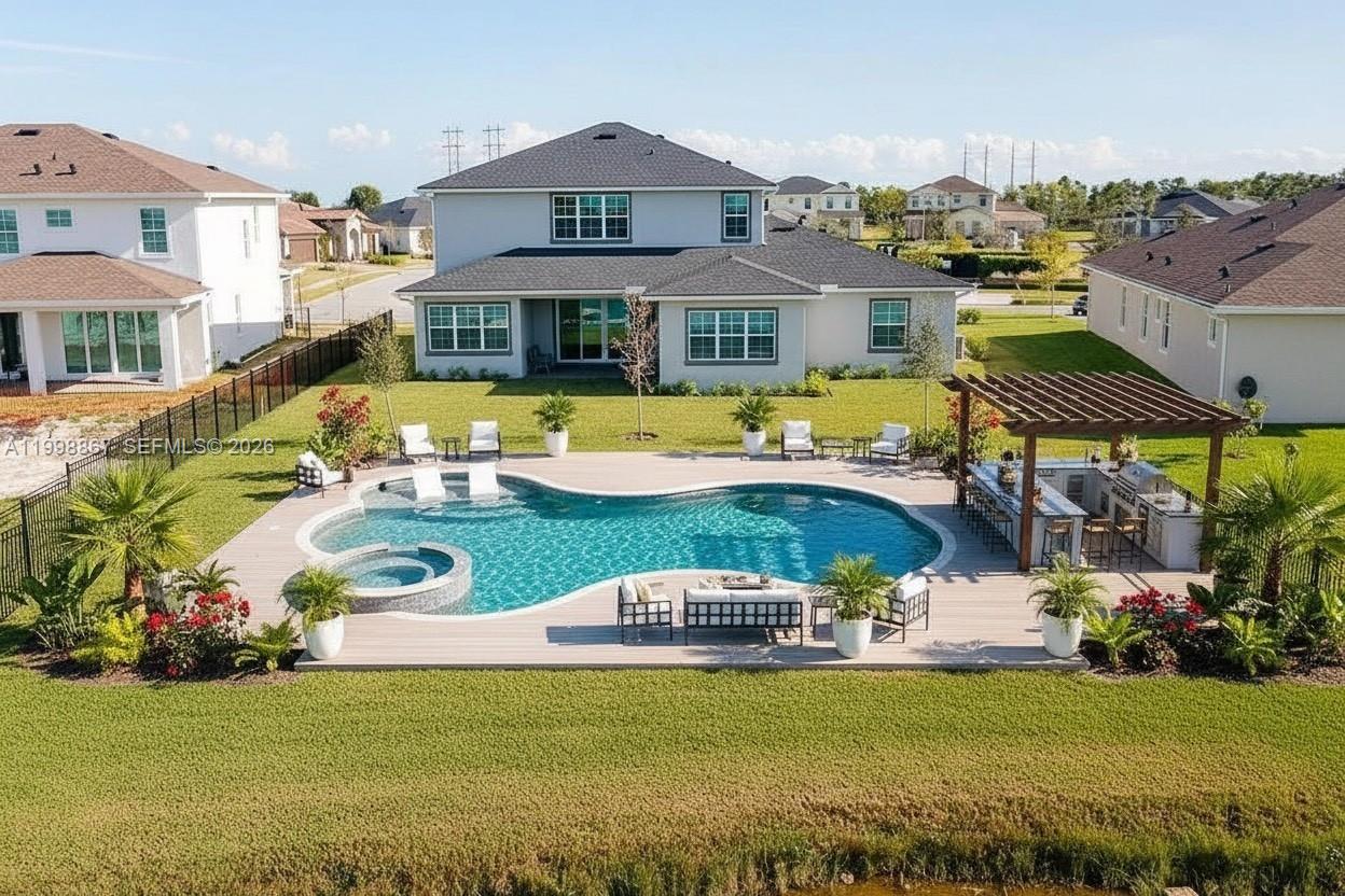 An aerial view of a backyard featuring a swimming pool, spa, and covered outdoor kitchen — 769 Hookline Cir, Loxahatchee FL 33470, LOXAHATCHEE, FL