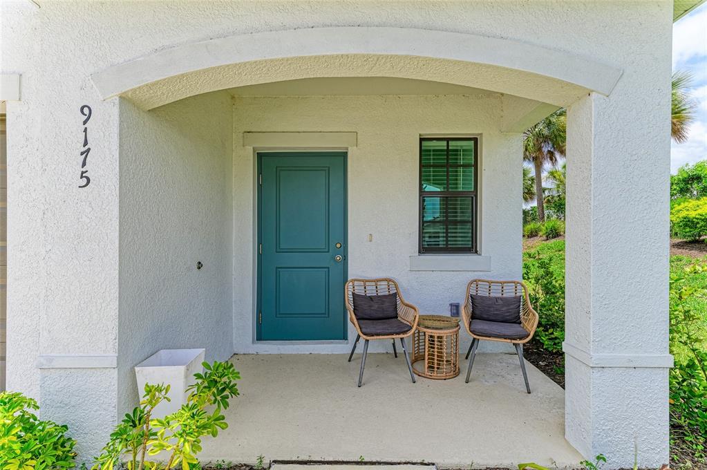 A two-story white house with a brown garage door and palm trees in the front yard — 9175 TEQUILA SUNRISE DRIVE, SARASOTA, FL