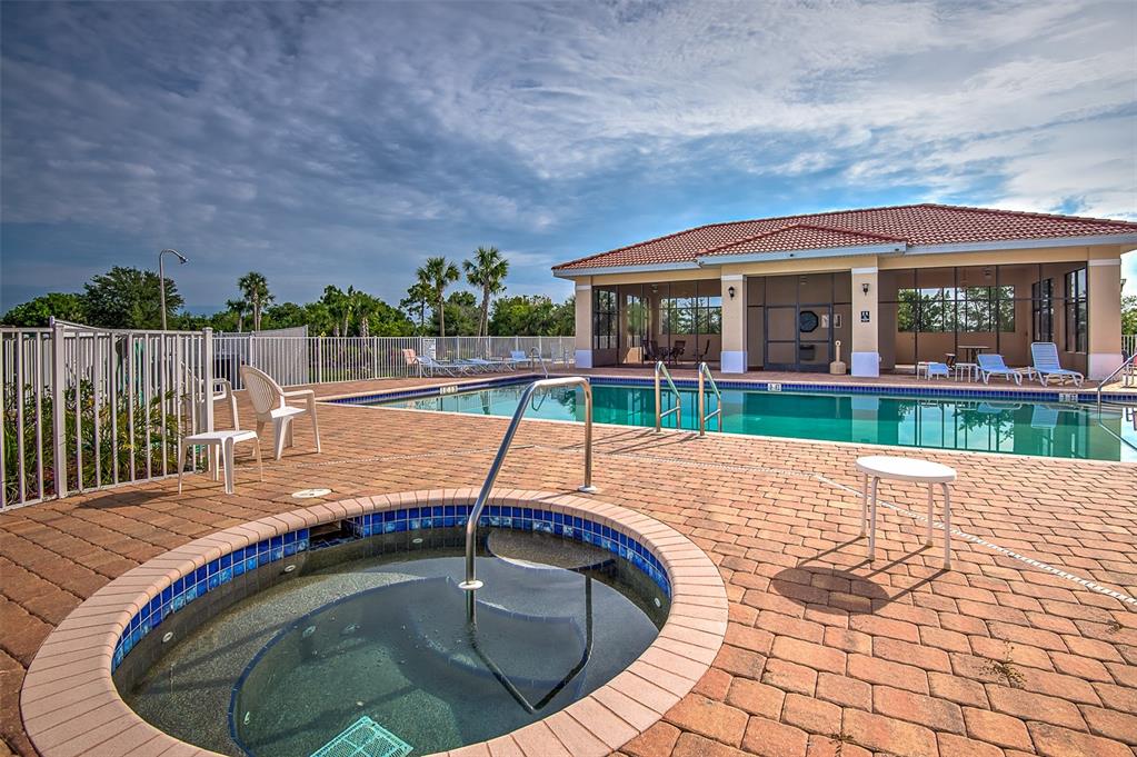 A circular hot tub sits on a brick patio beside a swimming pool and clubhouse — 240 W END DRIVE UNIT 713, PUNTA GORDA, FL