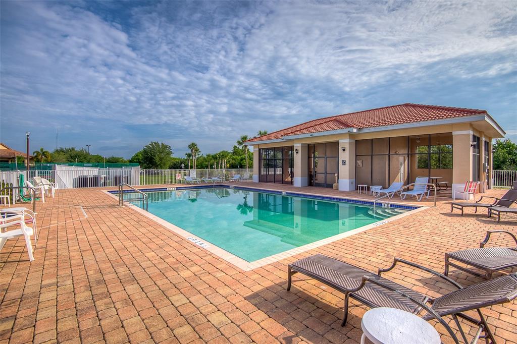 A swimming pool sits on a brick patio next to a clubhouse with a tiled roof — 240 W END DRIVE UNIT 713, PUNTA GORDA, FL