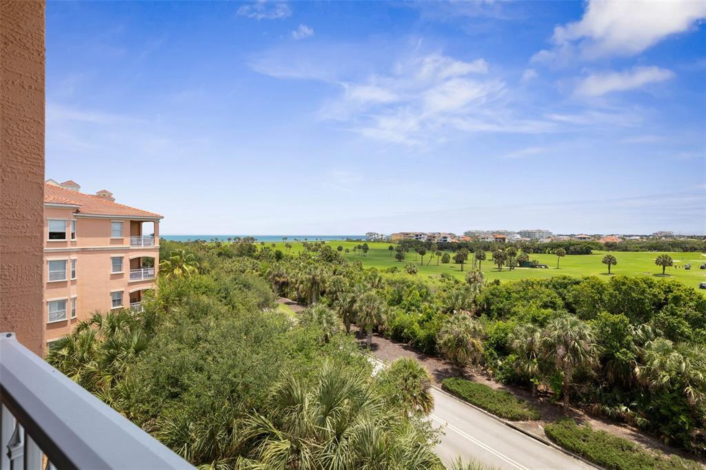 An elevated view from a balcony overlooking a golf course, lush vegetation, and the ocean — 25 OCEAN CREST WAY UNIT 1242, PALM COAST, FL