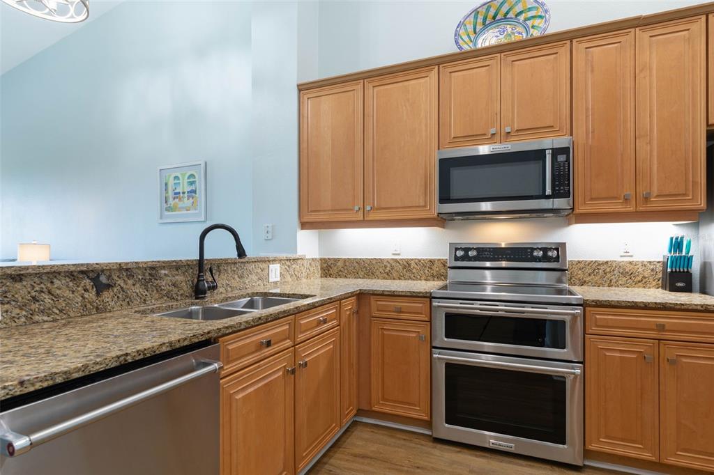 A kitchen features light wood cabinets, granite countertops, and stainless steel appliances — 25 OCEAN CREST WAY UNIT 1242, PALM COAST, FL