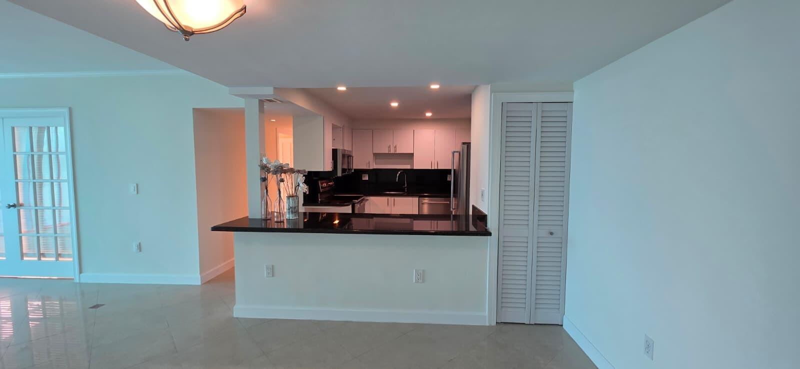 A multi-story beige apartment building features a paved circular driveway and lush tropical landscaping — 11111 Biscayne Boulevard # 4c, Miami FL 33181, MIAMI, FL
