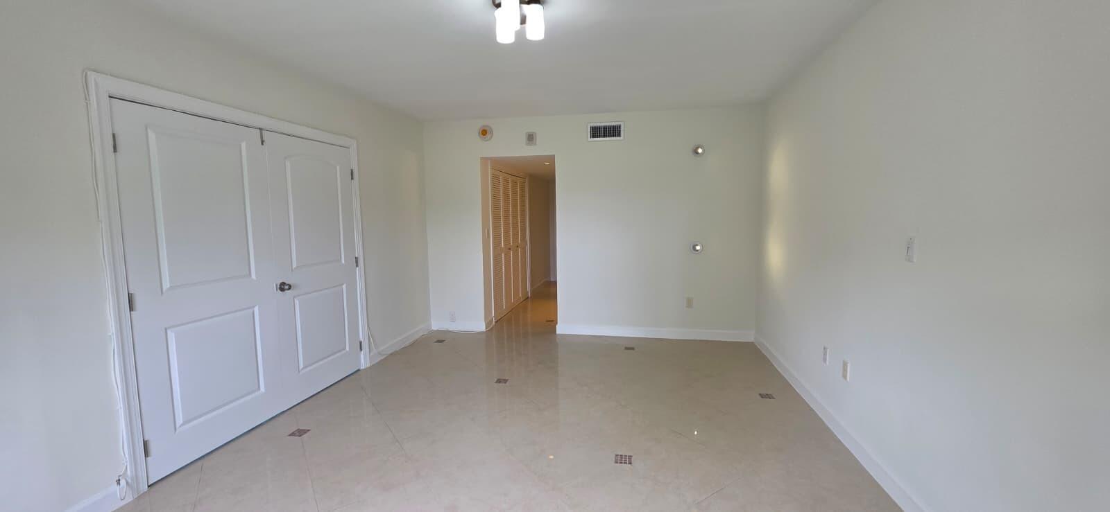 An open-concept living area features white tile floors, a kitchen with black countertops, and blue curtains — 11111 Biscayne Boulevard # 4c, Miami FL 33181, MIAMI, FL