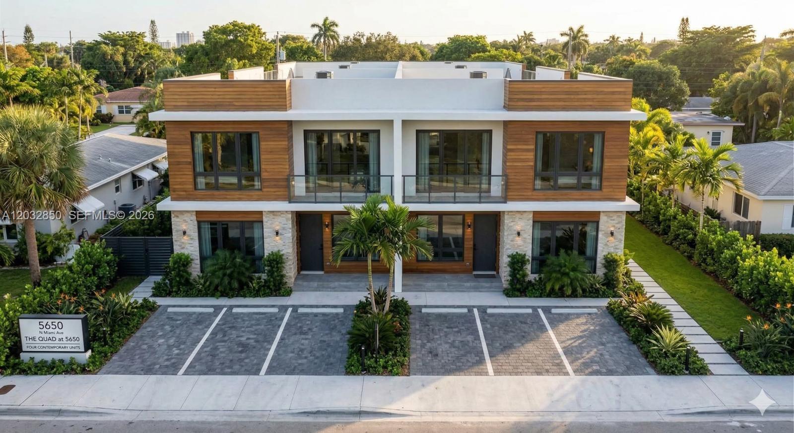 An exterior view of a modern two-story duplex with wood siding, stone accents, and parking — 5650 N Miami Ave, Miami FL 33127, MIAMI, FL